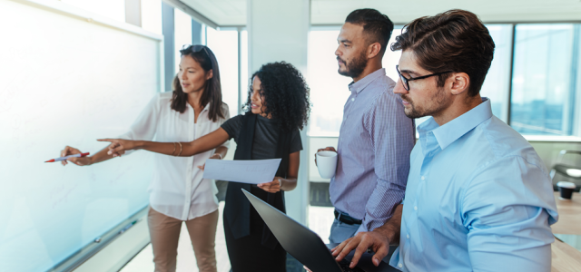 Group of people discussing beside a whiteboard